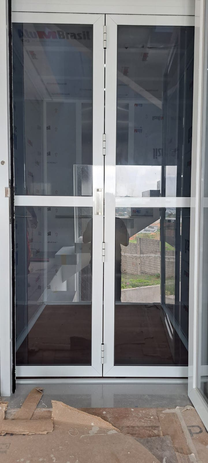 Elevador de carga com porta dupla pivotante de vidro em obra comercial