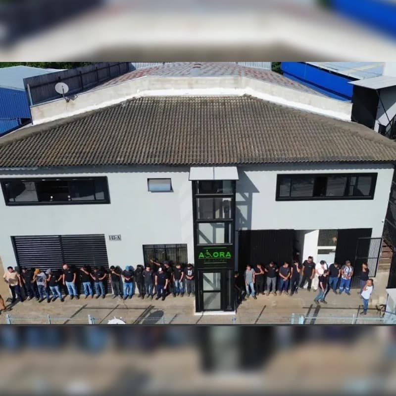 Fachada da fábrica em Atibaia com a equipe reunida na entrada