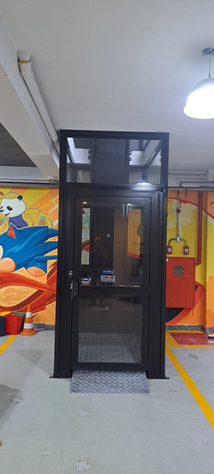 Plataforma hidráulica de acessibilidade com fechamento em vidro instalada em garagem comercial